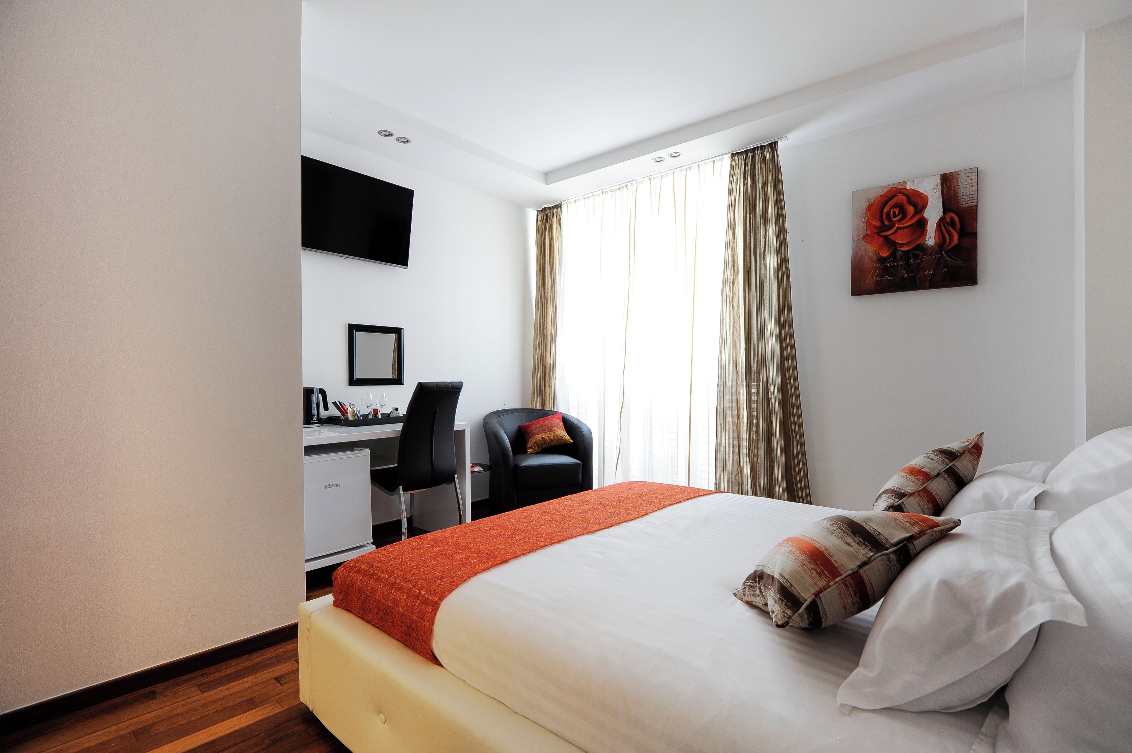 Una habitación de hotel con una cama, un escritorio, una silla y un televisor en la pared.