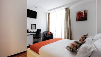 Una habitación de hotel con una cama, un escritorio, una silla y un televisor en la pared.