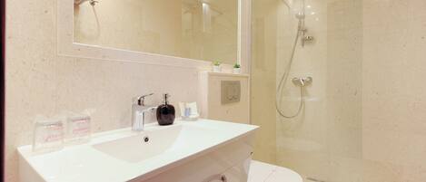 Un baño moderno con lavamanos, espejo y retrete blancos.
