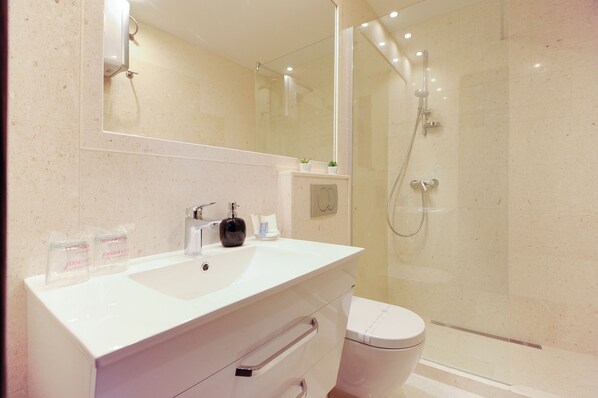 A modern bathroom with a white sink, mirror, and toilet. - Main street studio and rooms (Zadar)