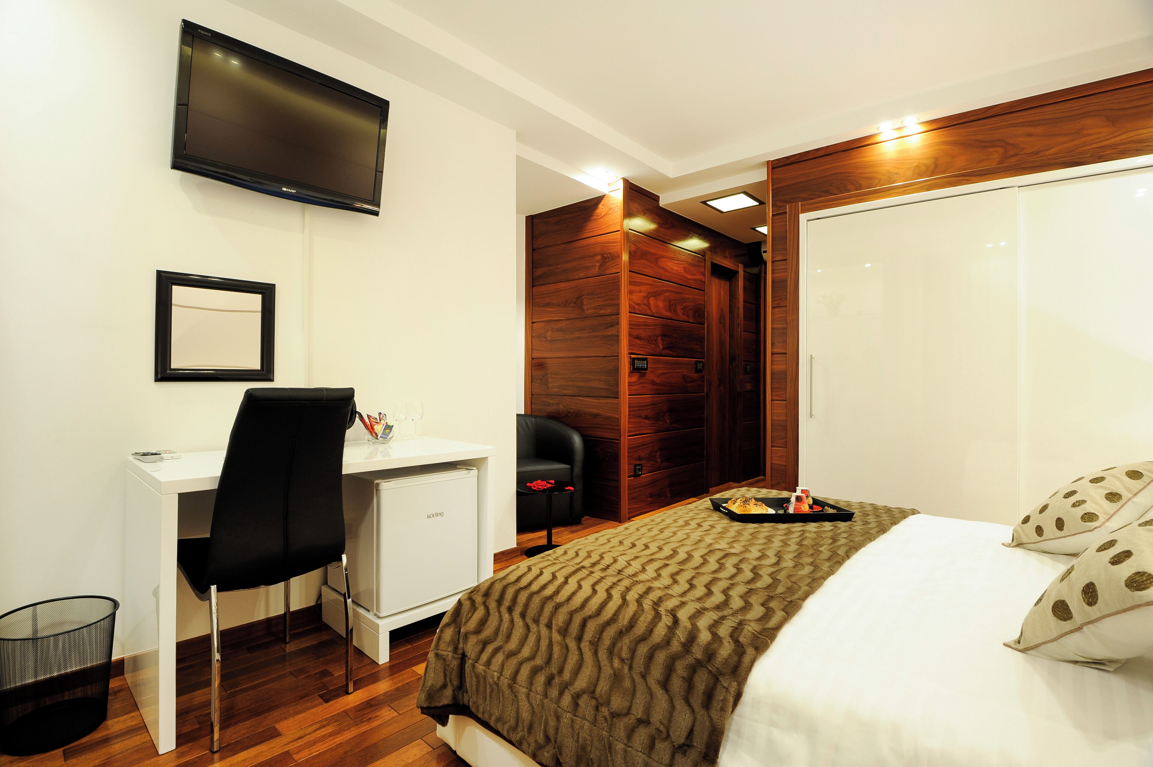 A hotel room with a bed, a desk, a chair, a TV, and a wardrobe.