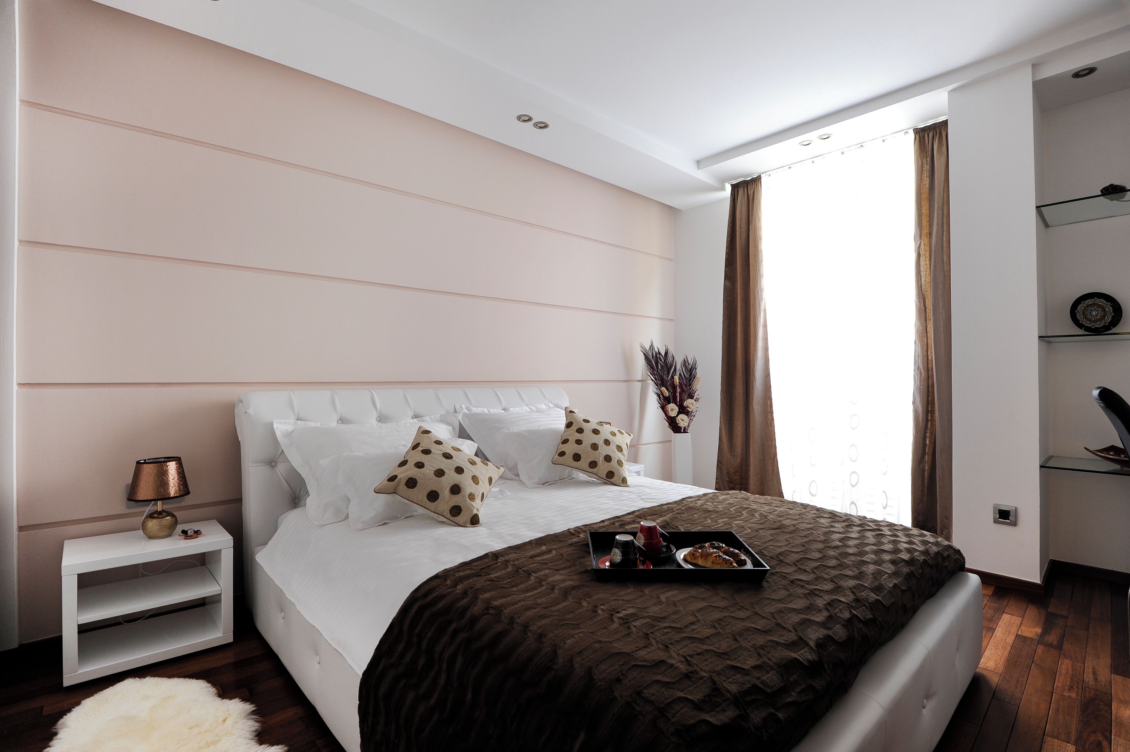 A modern bedroom with a large bed, a bedside table, and a nightstand.