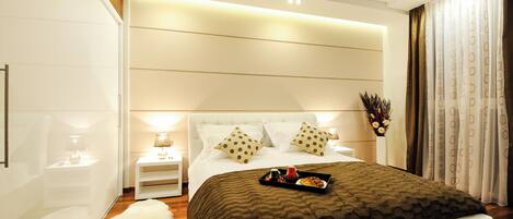 A modern bedroom with a large bed, bedside tables, a fluffy rug, and a nightstand with a lamp.