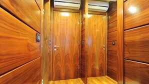 A wooden elevator interior with a polished floor and a closed door.