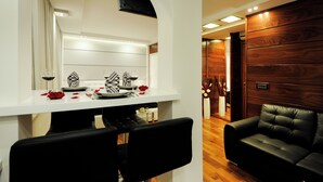 A modern dining area with a white table, black chairs, and a wooden wall.