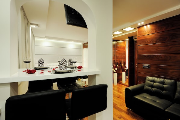 A modern dining area with a white table, black chairs, and a wooden wall.