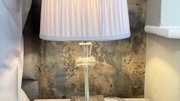 A clear glass table lamp with a ribbed lampshade on a textured wooden nightstand.
