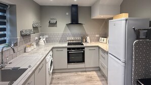 A compact kitchen with a built-in oven, a washing machine, and a refrigerator.