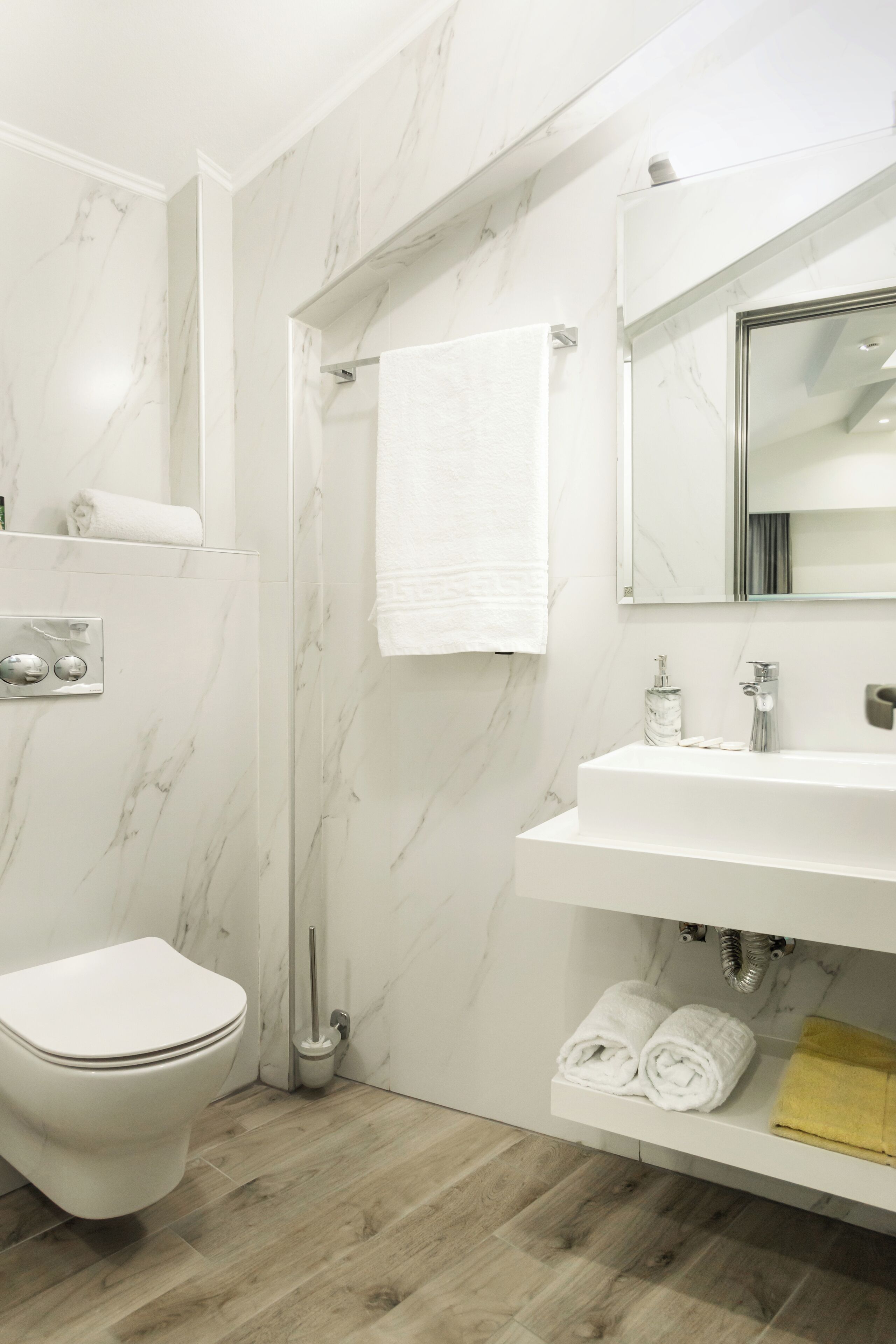 Un baño moderno con inodoro, lavamanos y espejo.