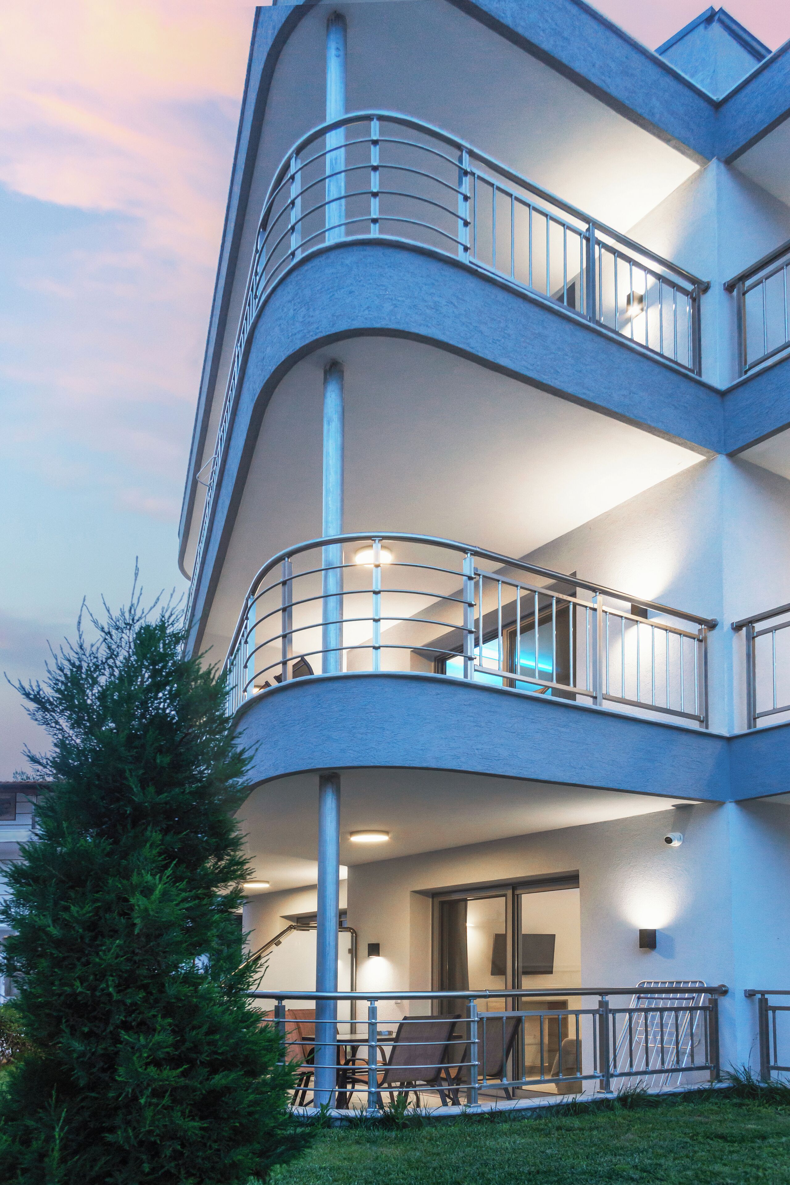 A multi-story building with balconies, a staircase, and a seating area with chairs and a table.