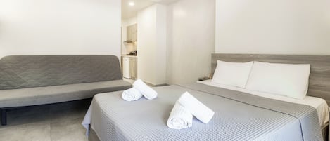 A modern hotel room with a bed, a sofa, and an air conditioning unit.