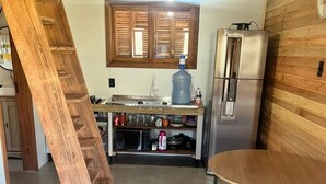 Eine Küche mit Holzvertäfelung, einem Edelstahl-Kühlschrank, einem Wasserspender und einer Mikrowelle.