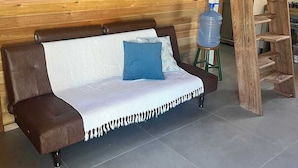 Eine Holzwand, eine Holzleiter und ein Sofa mit Decke und Kissen.
