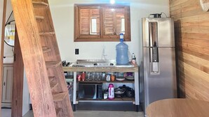 Eine Küche mit Holzbalken, einem großen Wasserspender, einem Kühlschrank und einer Mikrowelle.