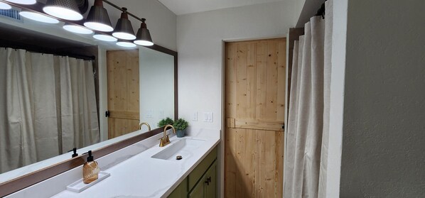 A bathroom with a white sink, a mirror, and a wooden door.