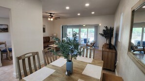 Un vaste espace dédié à la salle à manger, avec une table en bois, des chaises et un ventilateur de plafond.