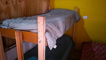 Una cama litera con estructura de madera, colchón gris y manta azul.