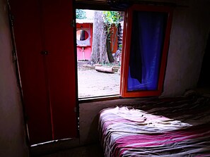 Una stanza con un letto, una finestra e una porta rossa.