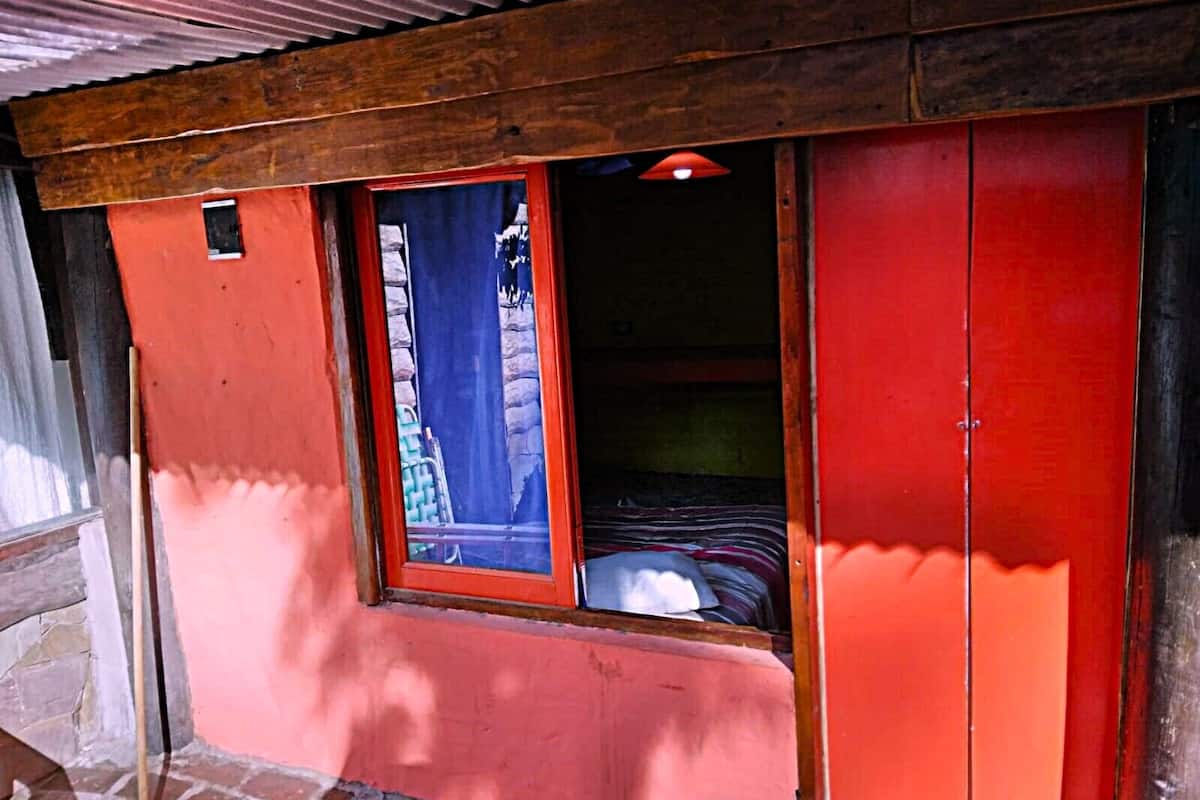 A room with a red exterior wall, a window with a blue curtain, and a wooden ceiling.