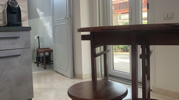 Una cocina con cafetera, una mesa de madera y una puerta que da a un balcón.