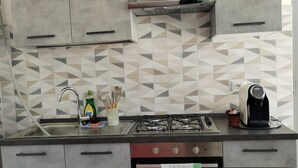 Una cocina con armarios grises, estufa a gas, horno empotrado y salpicadero de azulejos.