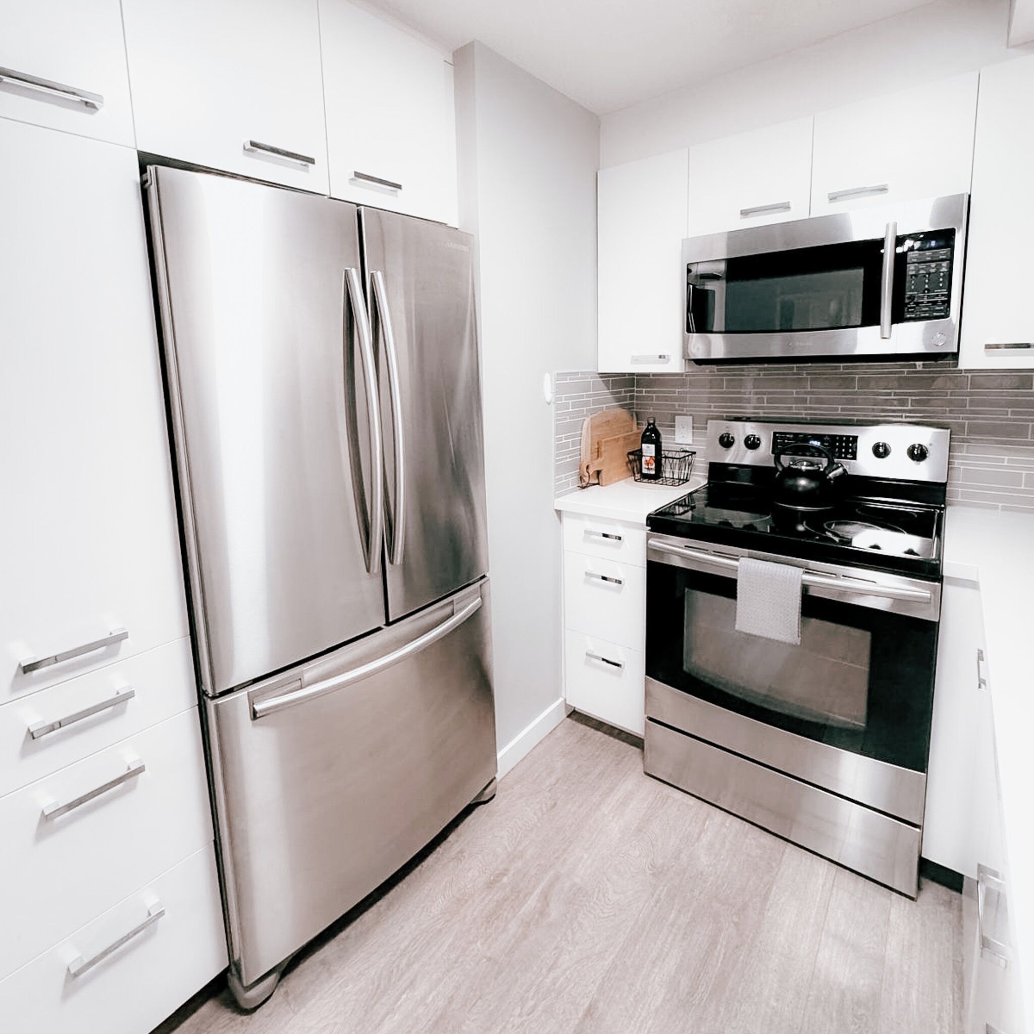 A modern kitchen with stainless steel appliances, including a refrigerator, microwave, and oven.
