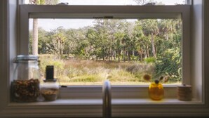 A window with a view of a natural landscape, a jar of nuts, and a small yellow vase. - Oak St Oasis - Minutes from Downtown and the beach! (Downtown St. Augustine)