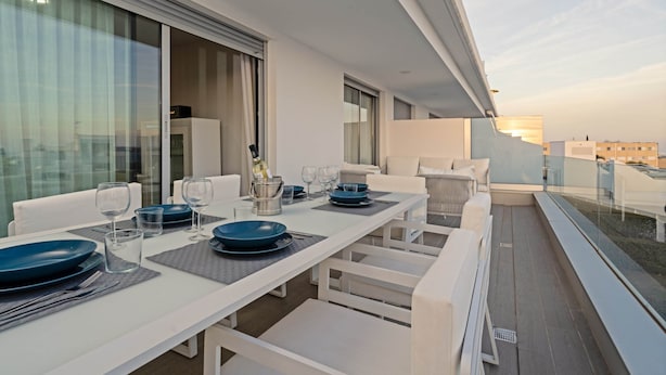 A modern dining area with a white table set for four, including plates, glasses, and cutlery. - Nice Apartment With Shared Pool (Estepona)