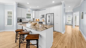 Una cocina moderna con armarios blancos, electrodomésticos de acero inoxidable y una isla grande con taburetes de bar.