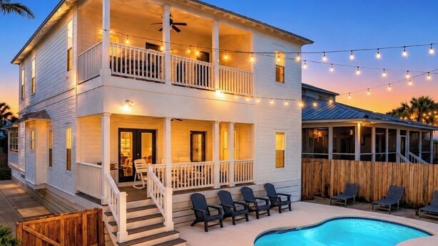 Una casa de dos pisos con balcón, piscina e iluminación festiva.