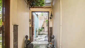 A narrow pathway leading to a building entrance with two stone Buddha statues on either side. - Perenan Villa - Two Bedroom Villa, Sleeps 4 (Pererenan)