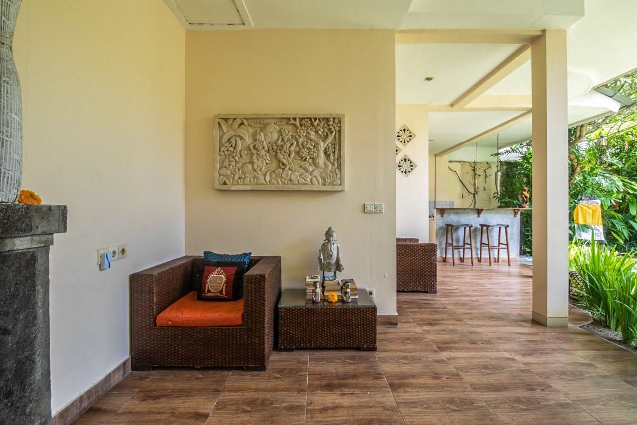 A living area with a wicker sofa, a small table with a Buddha statue, and a wall-mounted decorative piece.