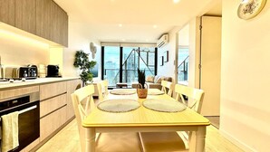 Cocina moderna con comedor, suelo de madera y vistas a la ciudad a través de amplios ventanales.