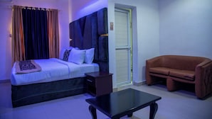 Een slaapkamer met een bed, een nachtkastje, een bank en een deur.