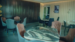 Een eetgedeelte met een marmeren tafel, beklede stoelen en een wand van houtpanelen.