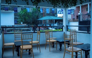 An outdoor seating area with bamboo chairs and tables, overlooking a cityscape with buildings and greenery. - Royal Winners Hotel (Port Harcourt)