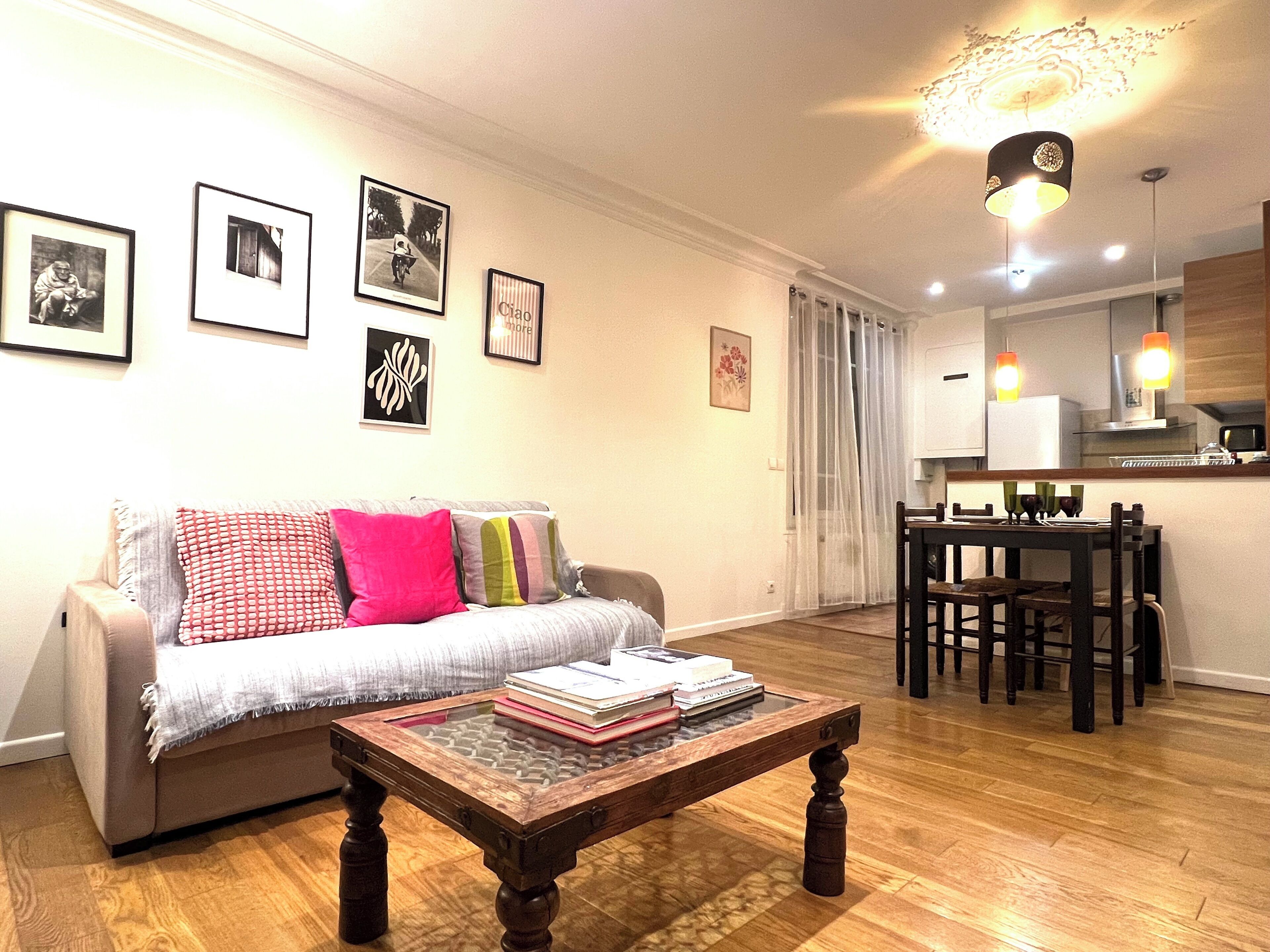 A living room with a sofa, a coffee table, and a dining area with chairs and a table.