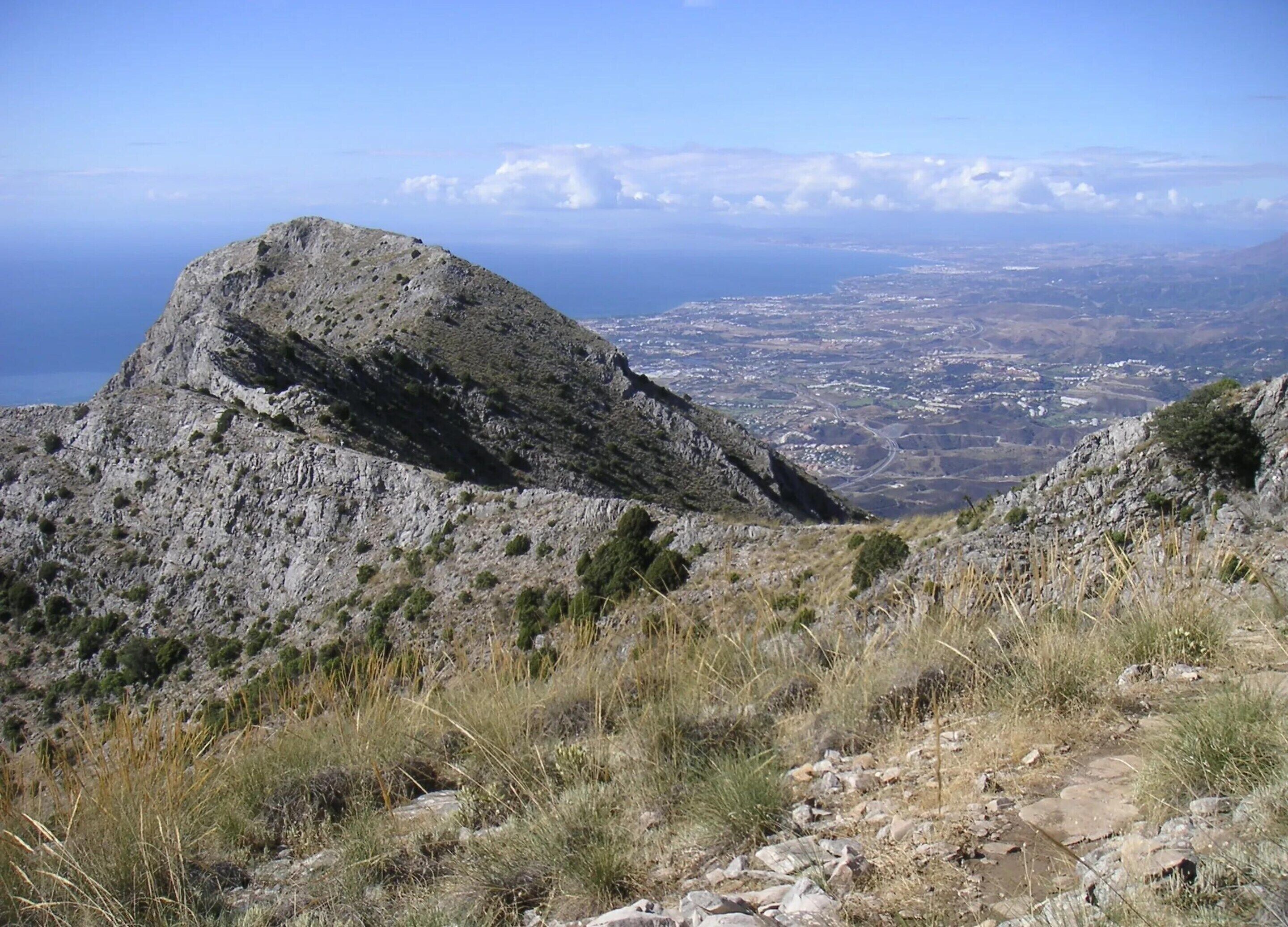 Un paysage montagneux rocheux offrant une vue dégagée sur une ville côtière située en contrebas.