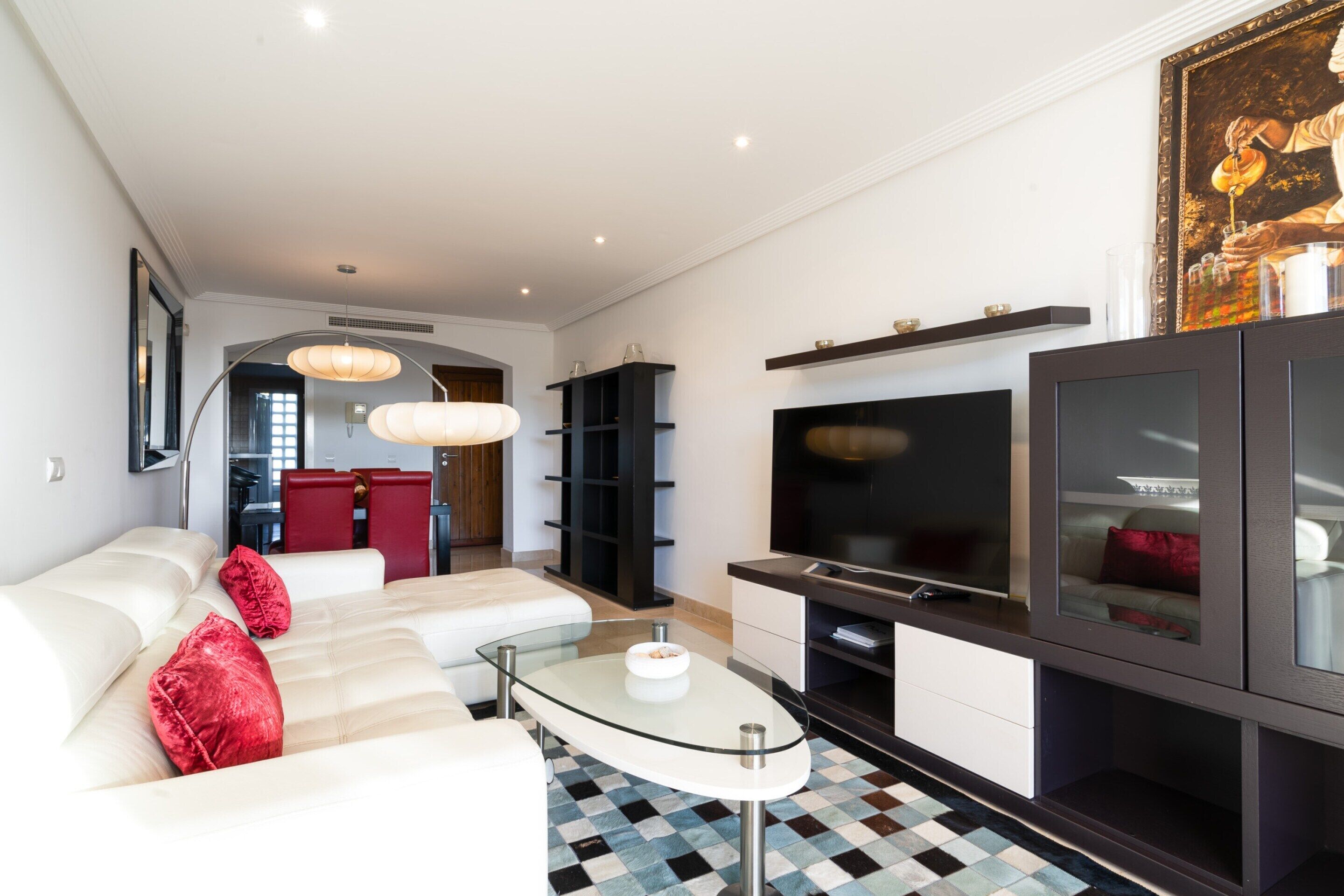 Een moderne woonkamer met een bank, een glazen salontafel, een flatscreen televisie en een zwarte entertainmentkast.