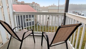 Un balcon avec deux chaises et une vue sur un parking et des immeubles.