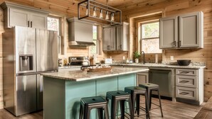 Une cuisine moderne dotée d’un îlot central, de tabourets de bar et d’appareils électroménagers intégrés.