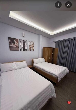Hotellihuone, jossa on kaksi sänkyä, vaatekaappi ja taideteoksia seinällä.