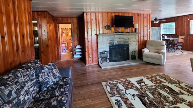 A cozy living room with a fireplace, wooden walls, a sofa, and a dining area. - The White Stag  (Hillsboro)