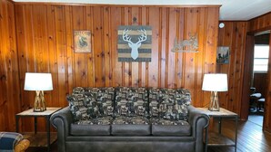A wooden-paneled room with a leather sofa, patterned cushions, and two lamps on side tables. - The White Stag  (Hillsboro)