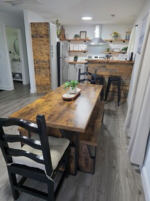 A modern kitchen with a wooden dining table, black chairs, and a built-in oven.
