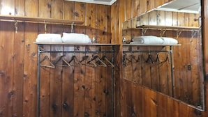 Una habitación con paneles de madera y un perchero metálico con toallas dobladas y perchas.