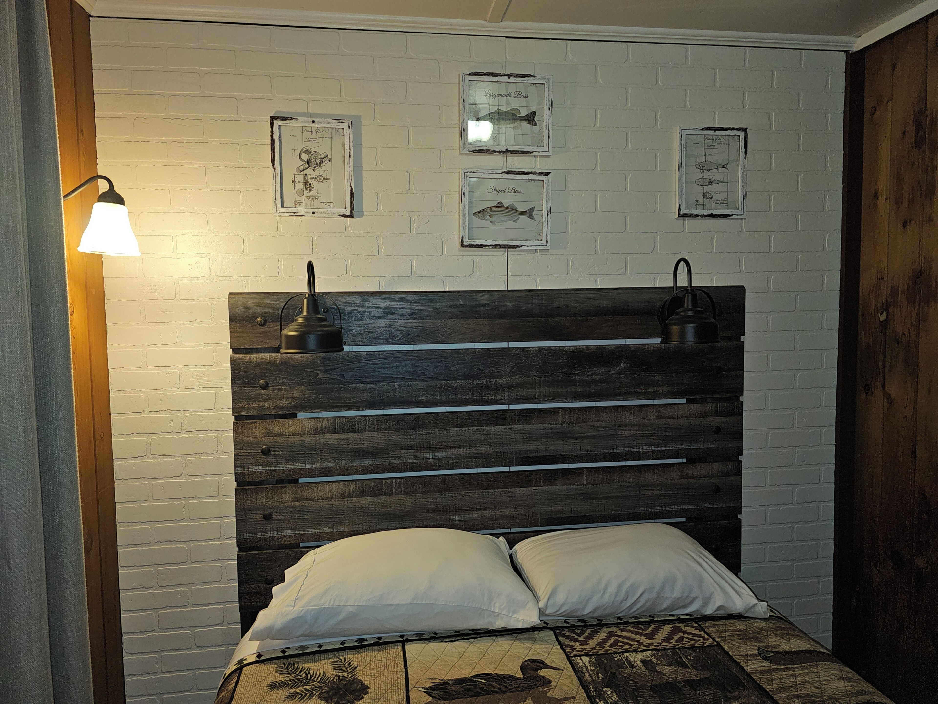 Un letto con una testiera in legno, cuscini bianchi e una coperta a motivi.