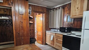 Una cocina de madera con una mesa de madera, un refrigerador, un microondas y una estufa.