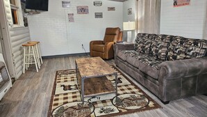Una sala acogedora con un sofá de cuero marrón, un tapete estampado y una mesa de centro de madera.