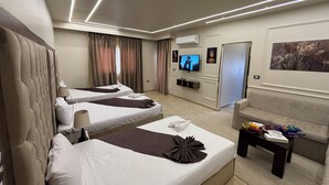 Habitación de hotel con dos camas, un televisor, una mesa de centro con frutas y un cuadro en la pared.